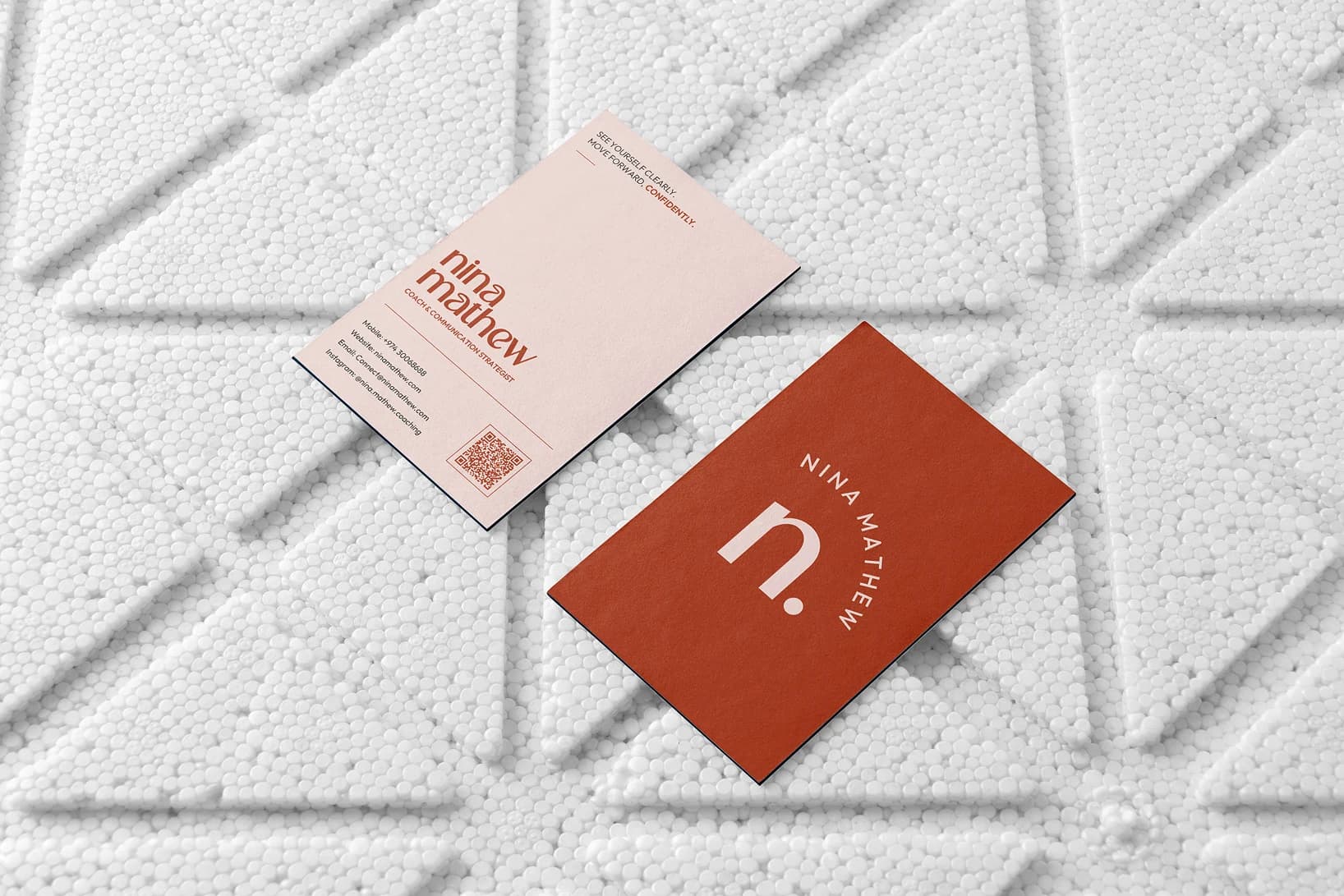 Nina Mathew business cards on a textured surface